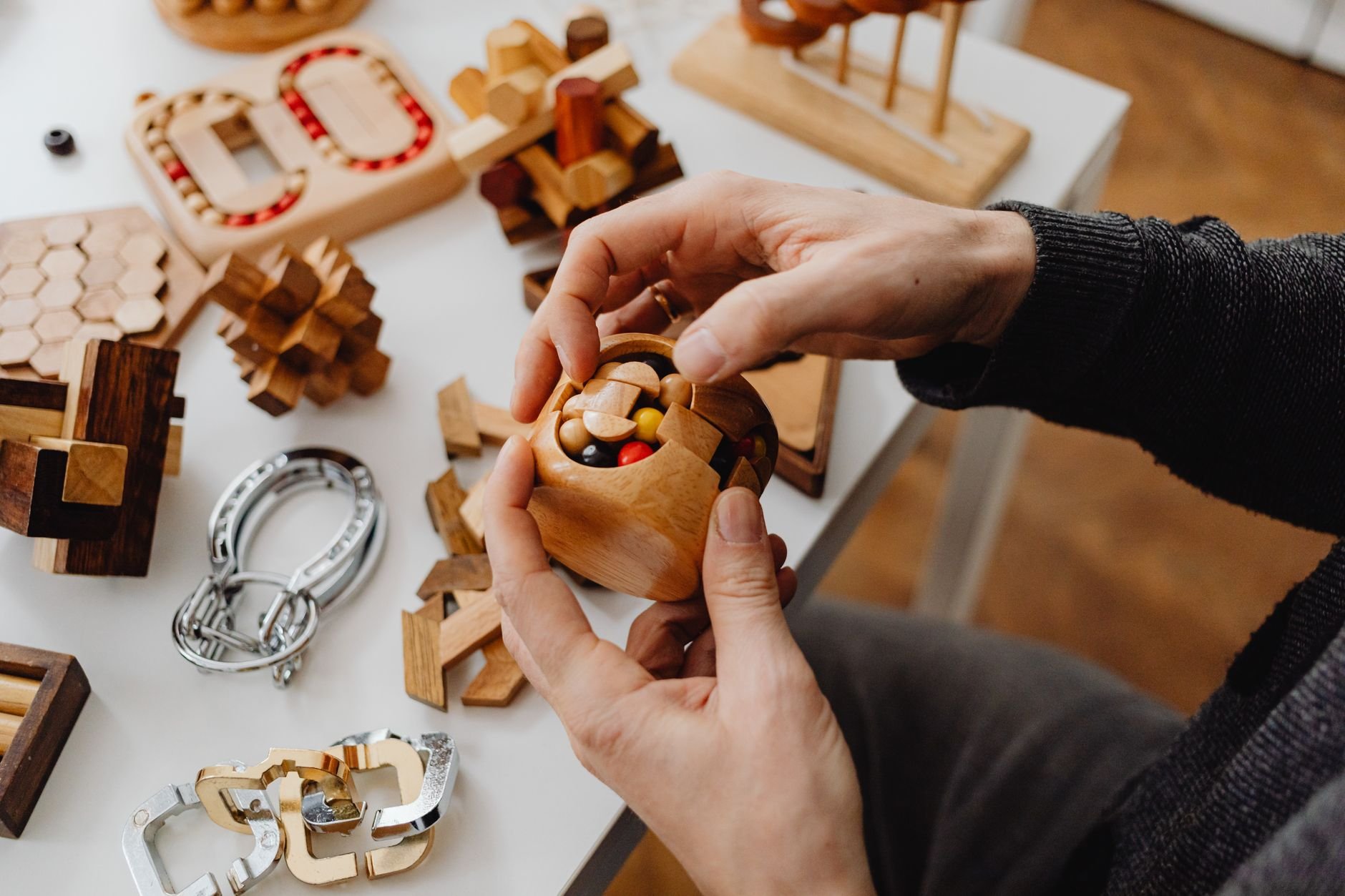 Person solving wooden puzzle with focused attention at a warm wooden desk
